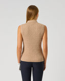 A woman viewed from the back wearing a sleeveless cable-knit mock-neck sweater vest in beige and dark navy leggings, against a light gray studio background.