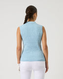 Woman wearing a light blue sleeveless sweater against a plain background