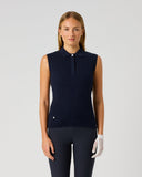 A woman modeling a sleeveless ribbed knit polo shirt in dark navy blue, paired with matching dark pants and a white glove, against a light gray studio background.
