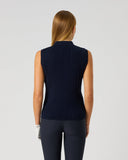 A woman viewed from the back wearing a sleeveless, ribbed knit mock neck top in dark navy blue, paired with dark leggings, against a light gray studio background.