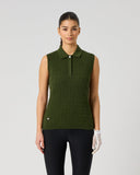 A woman modeling a sleeveless ribbed knit polo shirt in olive green, paired with black leggings and a white glove, against a plain light gray studio background.