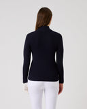 Person wearing a navy blue long-sleeve top and white pants on a light gray background