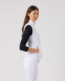 Woman wearing a white outfit with a black sleeve on a plain background