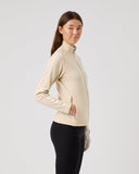 Woman wearing a beige jacket and black pants on a light gray background