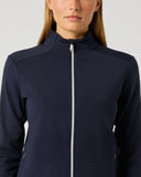 A woman wearing a dark navy blue athletic zip-up jacket with a high collar and a silver zipper, shown against a light gray studio background.