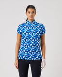 Woman wearing a blue patterned shirt and black pants on a gray background