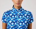 Woman wearing a blue and white patterned shirt against a gray background