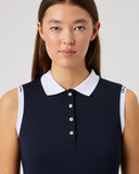 Woman wearing a navy sleeveless top with a white collar against a light gray background