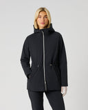 A woman modeling a black hooded jacket with a front zipper and drawstring waist, photographed against a plain light gray studio background.