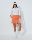 Person wearing a white shirt, orange skirt, and white shoes on a white background