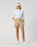 A woman modeling a white long-sleeve polo shirt, beige golf shorts, a white visor, white glove, and white sneakers against a light gray studio background.