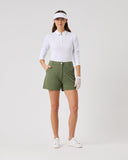 Woman in golf attire with a white shirt, green shorts, and visor on a light gray background
