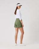Woman wearing a white long-sleeve shirt, green shorts, and a visor on a white background
