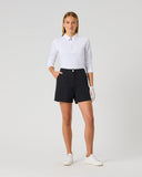 A woman modeling a white long-sleeve polo shirt and black shorts against a light gray studio background.