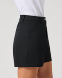 A person wearing black tailored shorts with a white top, shown from the waist to mid-thigh against a plain light gray studio background.