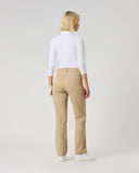 A woman is shown from the back wearing beige straight-leg trousers, a white long-sleeve mock neck top, and white sneakers, standing against a light gray studio background.