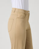 A side view of a model wearing beige high-waisted trousers and a white top, shown against a light gray studio background.