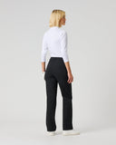 A blonde woman is shown from the back wearing a white long-sleeve mock neck top, black trousers, and white sneakers, standing against a light gray studio background.