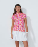 Woman wearing a colorful floral blouse and white skirt on a plain background