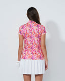 Woman wearing a colorful floral dress and white skirt on a plain background