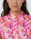 Woman wearing a colorful patterned shirt against a plain background