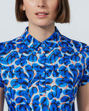 Person wearing a blue patterned shirt against a plain background