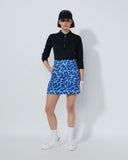 Person wearing a black top and blue patterned skirt on a white background