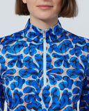 Person wearing a blue patterned long-sleeve top against a plain background