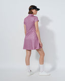 Person wearing a pink checkered dress and black cap on a white background