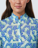 Woman wearing a blue and green patterned shirt against a plain background