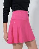 Person wearing a black long-sleeve top and pink skirt on a plain background