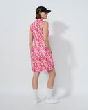 Person wearing a pink floral dress and black cap on a white background