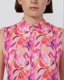 Person wearing a sleeveless, floral-patterned top with a zipper on a plain background