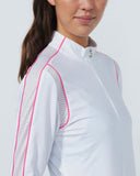 Woman wearing a white shirt with pink accents on a plain background
