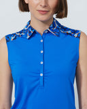 Woman wearing a blue sleeveless top with patterned collar against a plain background