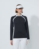 Woman wearing a black and white golf outfit with a visor on a light gray background