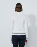 Person wearing a white long-sleeve top and dark pants on a light gray background