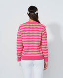 Person wearing a pink and white patterned sweater on a plain background