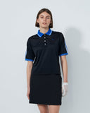 Woman wearing a black polo shirt with blue accents and a matching skirt on a white background