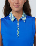 Woman wearing a blue sleeveless top with a patterned collar against a plain background