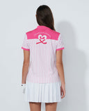 Woman wearing a pink and white striped polo shirt with a heart design on the back, standing against a plain background.