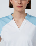 Woman wearing a white and light blue shirt against a plain background