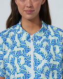 Person wearing a patterned shirt with blue and white design on a plain background