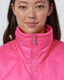 Person wearing a pink puffer vest against a white background