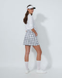 Woman in golf attire with a white shirt, checkered skirt, and visor on a light gray background