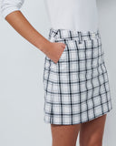 Person wearing a white plaid skirt on a plain background