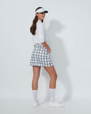 Woman in golf attire with a white shirt, checkered skirt, and visor on a light gray background
