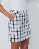 Person wearing a white plaid skirt on a plain background
