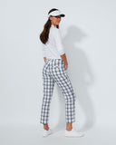 Woman wearing a white outfit with plaid pants on a plain background
