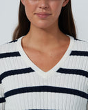 Woman wearing a white sweater with navy blue stripes against a plain background